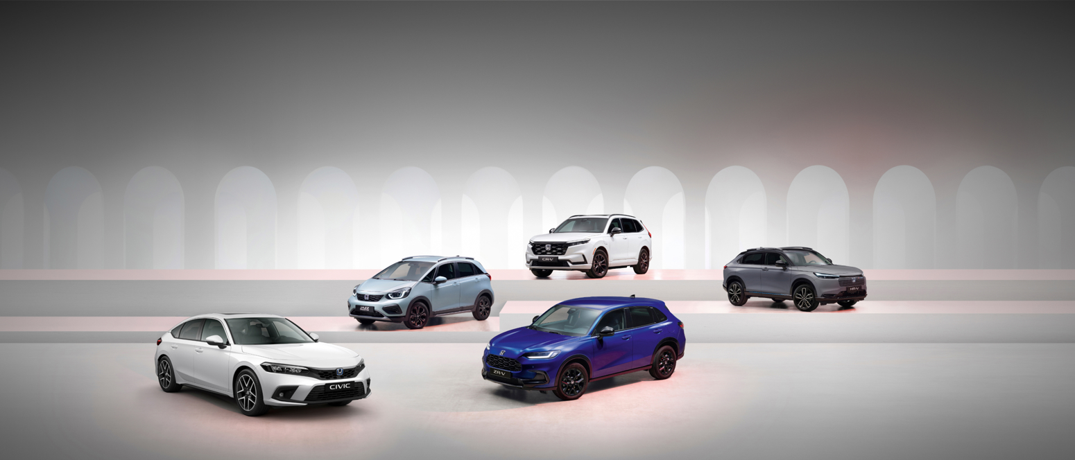 Five Honda vehicles, including sedans and SUVs, are showcased in a modern showroom featuring an arched backdrop.
